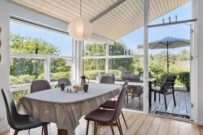 a dining room with a table and chairs and windows at JB403-Fjerritslev-Poppelvej-20 in Fjerritslev