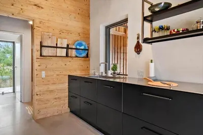 a kitchen with black cabinets and a wooden wall at LK2174-Lokken-Stellavej-18 in Løkken
