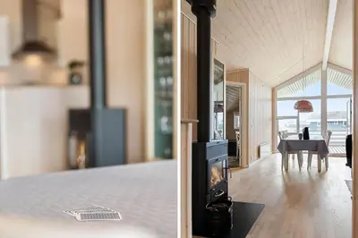 a living room with a fireplace and a dining room at 814-Harboore-Neerlandiavej-176 in Harboør