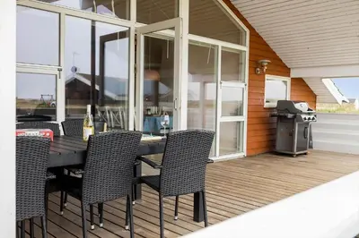 a patio with a table and chairs on a deck at 814-Harboore-Neerlandiavej-176 in Harboør