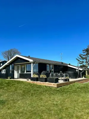 a house with a deck with chairs in front of it at Beach Hotel Inspired Holiday Home By Limfjorden in Snedsted