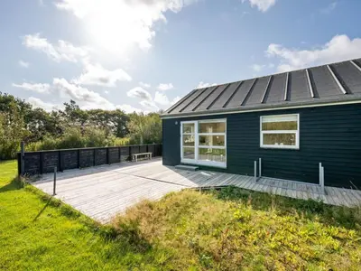 a black house with a wooden deck next to a field at Holiday Home Anja - 550m to the fjord by Interhome in Vemb
