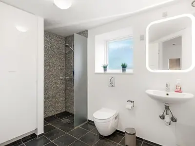 a white bathroom with a toilet and a sink at Holiday Home Raika - 25m to the fjord by Interhome in Vestervig