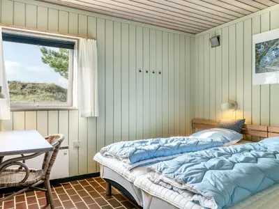 two beds in a room with a table and a window at Apartment Enwald - 700m from the sea by Interhome in Pandrup