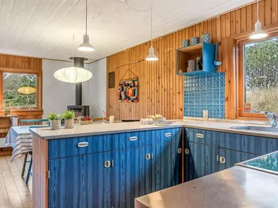 a large kitchen with blue cabinets and a table at Holiday Home Anneka - 750m from the sea by Interhome in Pandrup