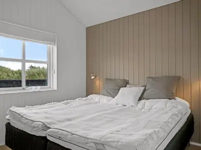 a large white bed in a room with a window at Holiday Home Alde - 150m from the sea by Interhome in Blokhus