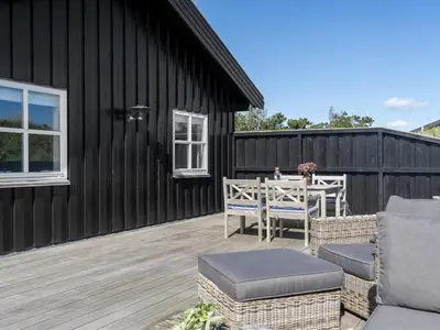 a patio with a table and chairs on a wooden deck at Holiday Home Alde - 150m from the sea by Interhome in Blokhus