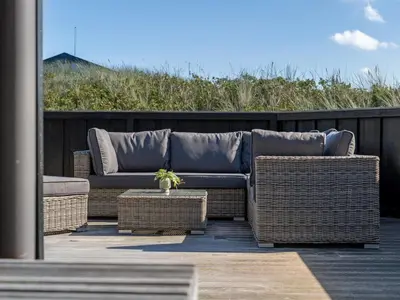 a couch sitting on a patio with wicker furniture at Holiday Home Alde - 150m from the sea by Interhome in Blokhus