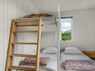 two bunk beds in a room with a window at Holiday Home Myrna - 250m from the sea by Interhome in Saltum