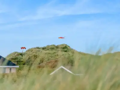 an airplane flying over a hill with a house at Holiday Home Myrna - 250m from the sea by Interhome in Saltum