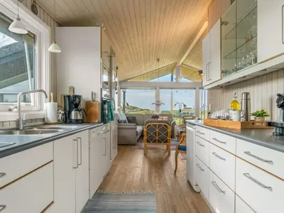 a kitchen with white cabinets and a living room at Holiday Home Myrna - 250m from the sea by Interhome in Saltum