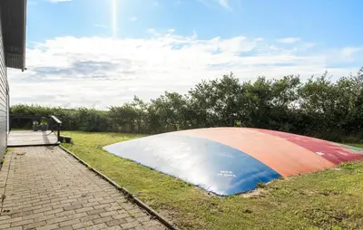a large object laying on the grass next to a building at Awesome Home In Harboøre With Sauna in Harboør