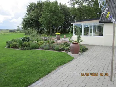 a garden with flowers and plants in front of a house at Bakkegården Homestay in Spottrup