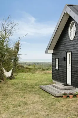 a small black house with a porch and a window at Family House With Sea View In Svinkløv in Fjerritslev