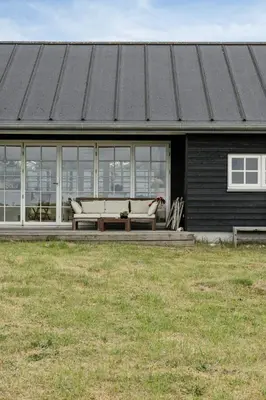 a house with a bench on the front of it at Family House With Sea View In Svinkløv in Fjerritslev