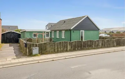 a green house with a wooden fence on a street at Lovely Home In Thyborøn With Wifi in Thyborøn