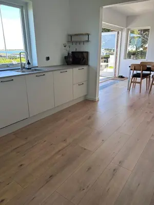 a kitchen with white cabinets and a wooden floor at Udsigtsvilla Tambohus in Thyholm