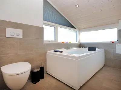 a bathroom with a white tub and a toilet at Holiday Home Arisa - 100m to the fjord by Interhome in Løgstør