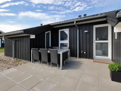 a black house with a table and chairs on a patio at Holiday Home Arisa - 100m to the fjord by Interhome in Løgstør