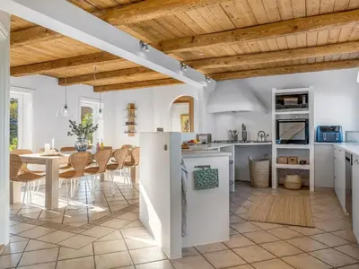 a kitchen and dining room with white walls and wooden ceilings at Holiday Home Elida - 400m from the sea by Interhome in Hanstholm