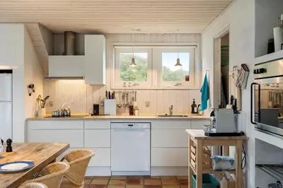 a kitchen with white appliances and a wooden table at BL1120-Saltum-Kohlsvej-15 in Saltum