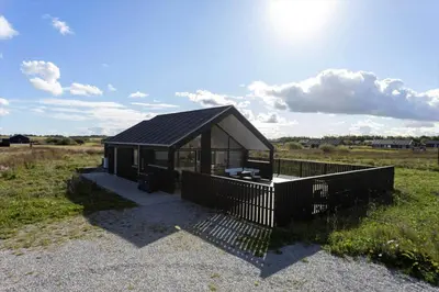 a small house with a black roof in a field at LK2159-Lokken-Kringelbaekvej-27 in Løkken