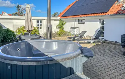 a bath tub on a patio with an umbrella at 3 Bedroom Nice Home In Blokhus in Blokhus