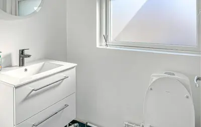 a bathroom with a sink and a toilet and a mirror at 3 Bedroom Nice Home In Blokhus in Blokhus