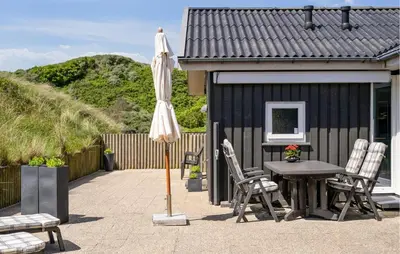 a patio with an umbrella and a table and chairs at Beautiful Home In Blokhus With Sauna in Blokhus
