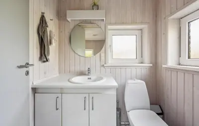 a bathroom with a sink and a toilet and a mirror at Beautiful Home In Blokhus With Sauna in Blokhus