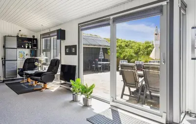 a patio with sliding glass doors and a table and chairs at Beautiful Home In Blokhus With Sauna in Blokhus