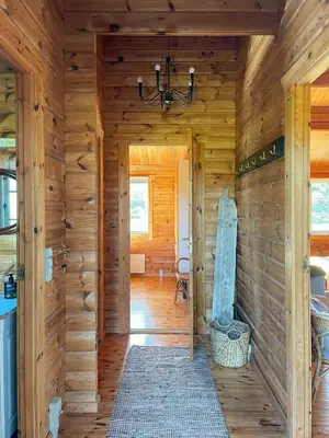 a hallway of a log cabin with a chandelier at Authentic Wooden House By The North Sea in Vestervig