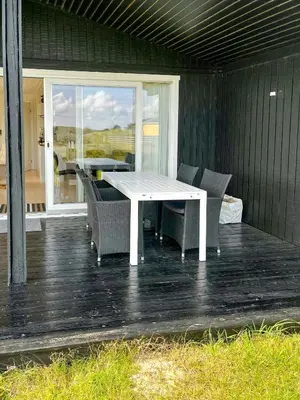 a patio with a white table and chairs on a deck at Family House Close To The Sea At Tranum Strand in Brovst
