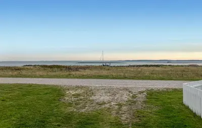 a gravel road in a field with the ocean in the background at Cozy Home In Struer With Sauna in Struer