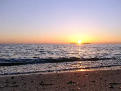 a sunset over the ocean with a sandy beach at 4 star holiday home in Løgstør in Løgstør