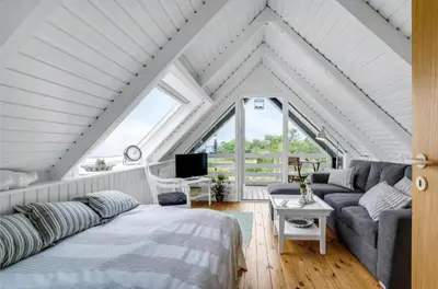 a attic bedroom with a bed and a couch at Fjord Views And Spa By Limfjorden in Roslev