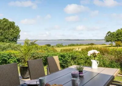 a dining table with a view of the water at Fjord Views And Spa By Limfjorden in Roslev