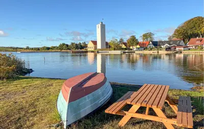 a boat sitting on the side of a lake with a bench at 3 Bedroom Gorgeous Home In Hurup Thy in Doverodde