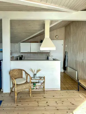 a kitchen with a rattan chair and a table at Bright Holiday Home Close To Sea Near Blokhus in Blokhus