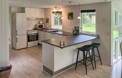 a kitchen with a large counter and stools in it at 3 Bedroom Awesome Home In Højslev in Højslev