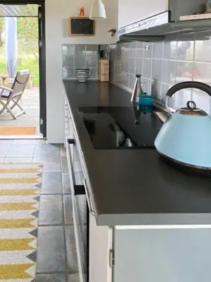 a kitchen with a black counter top with a sink at Summerhouse By The Heath Near The North Sea in Snedsted