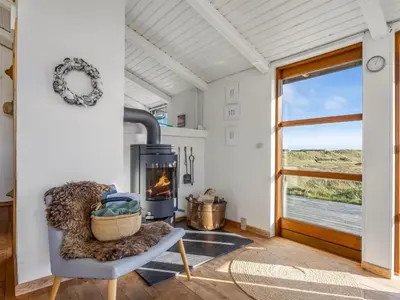 a living room with a fireplace and a chair at Holiday Home Sigbritt - 750m from the sea by Interhome in Løkken