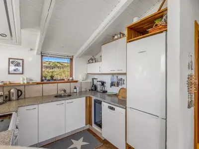 a kitchen with white cabinets and a white refrigerator at Holiday Home Sigbritt - 750m from the sea by Interhome in Løkken