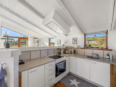 a kitchen with white cabinets and a vaulted ceiling at Holiday Home Sigbritt - 750m from the sea by Interhome in Løkken