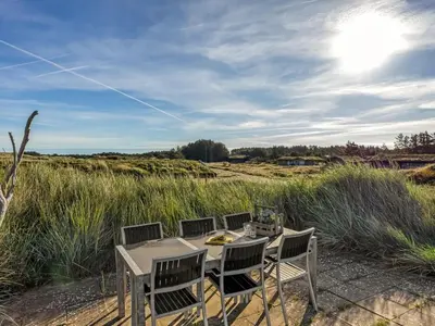 a table and chairs on the sand near a field at Holiday Home Sigbritt - 750m from the sea by Interhome in Løkken