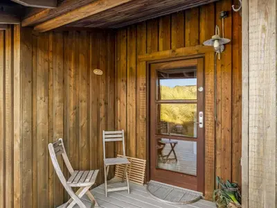a porch of a wooden house with two chairs and a door at Holiday Home Sigbritt - 750m from the sea by Interhome in Løkken