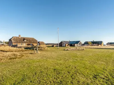 a field with houses in the background and a house at Holiday Home Amber - 300m from the sea by Interhome in Harboør