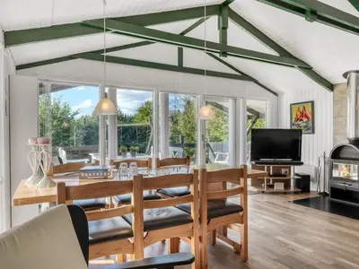 a dining room with a table and chairs and a tv at Holiday Home Inola - 3-5km from the sea by Interhome in Fjerritslev
