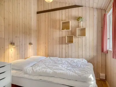 a bedroom with a white bed in a wooden wall at Holiday Home Inola - 3-5km from the sea by Interhome in Fjerritslev