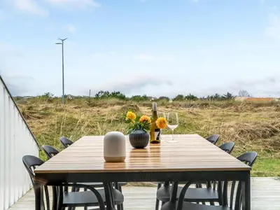 a wooden table with flowers and wine glasses on a deck at Holiday Home Adelbrand - 1km from the sea by Interhome in Blokhus